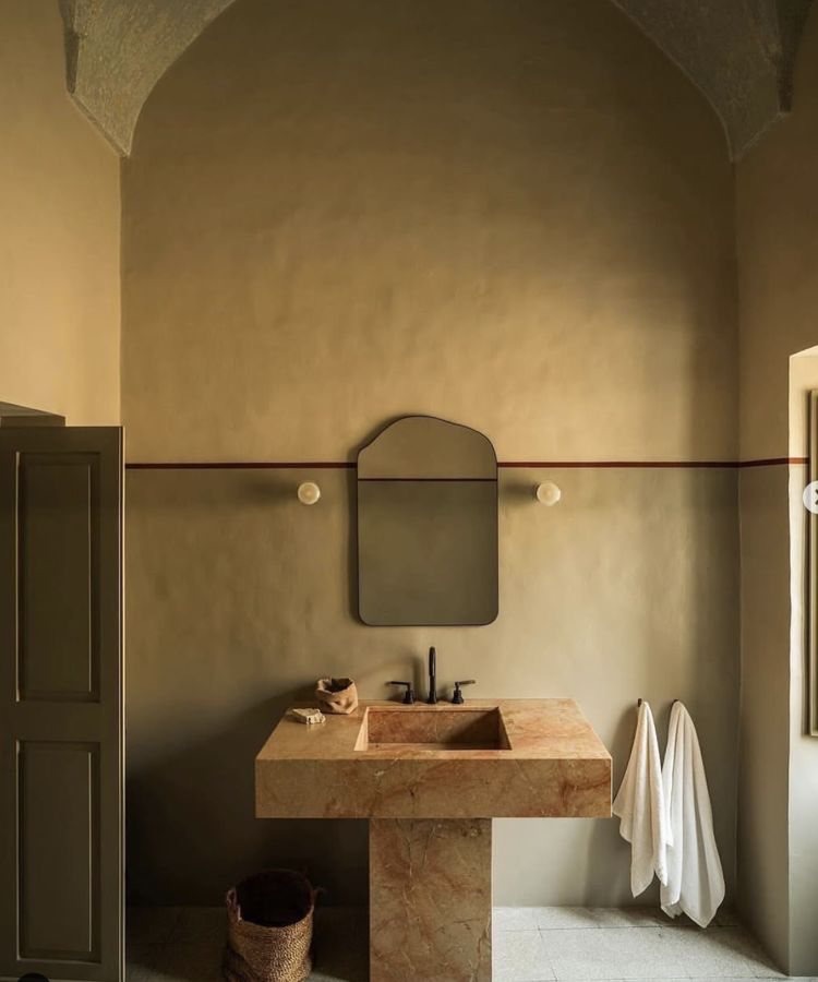 A lime-plastered bathroom with a stone basin